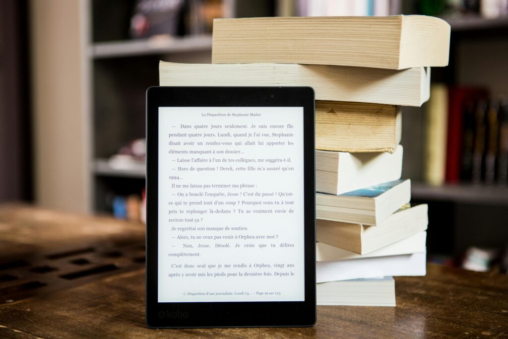 Kindle in front of a pile of books.